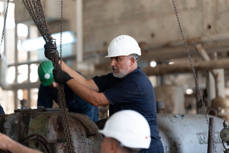 man in a hard hat grabbing several medium sized chains and pulling down
