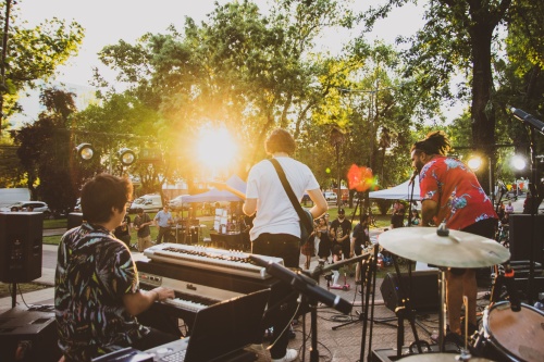 band on stage with guys playing the keyboard, guitar and drums in front of a small crowd