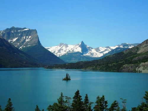 landscape with a lake in the foreground with snow covered mountains in the distance